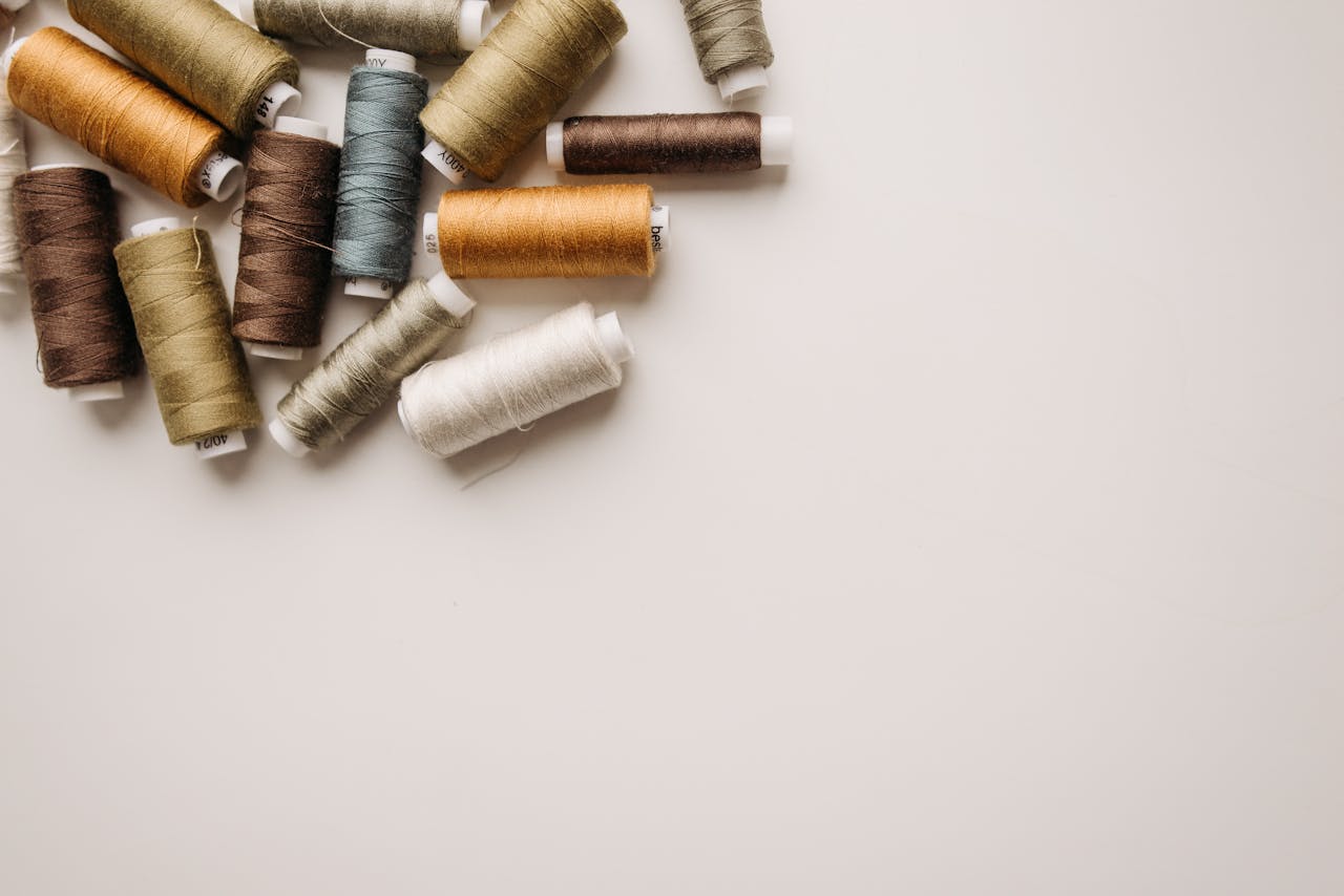 our-services-3 Top view of various colored spools of thread on a white background.